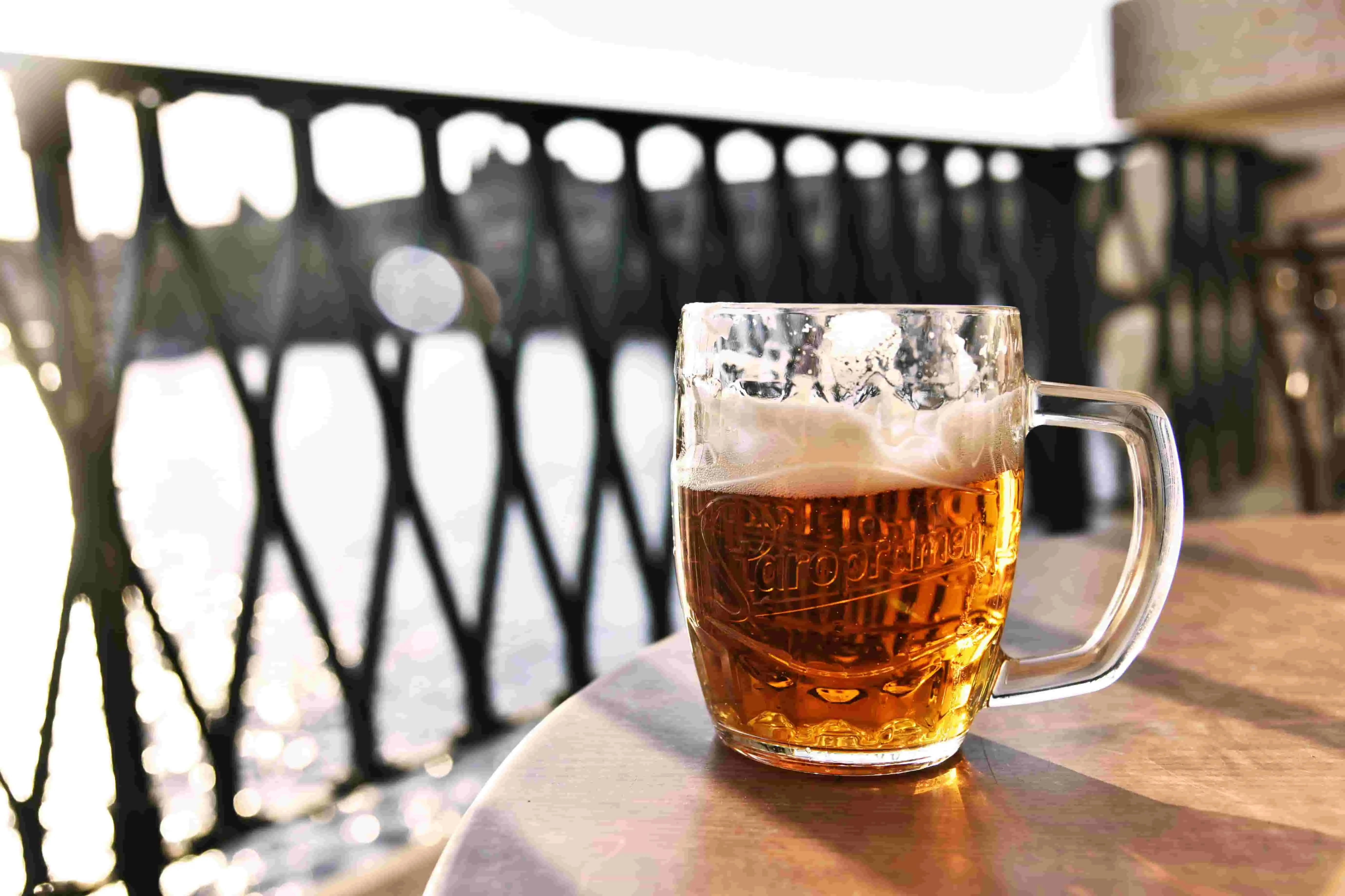Picture of a tankard of beer on a wooden table in front of a railing